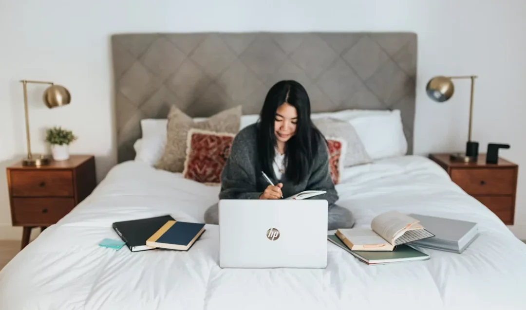 Étudiante travaillant sur son mémoire avec un ordinateur portable et des livres